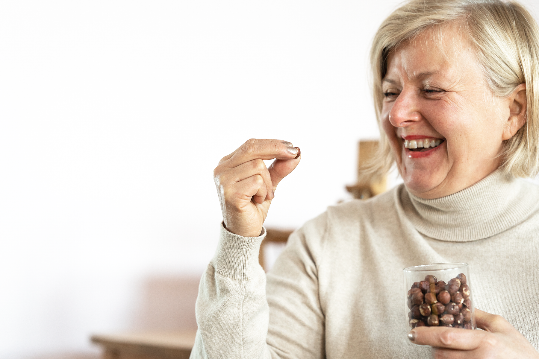 Nainen nauraa hasselpähkinä kädessään