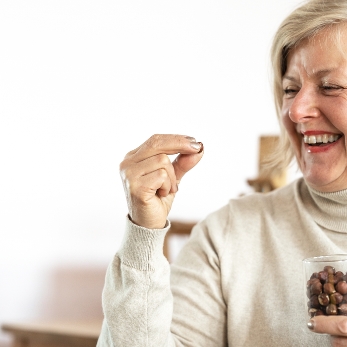 Nainen nauraa hasselpähkinä kädessään